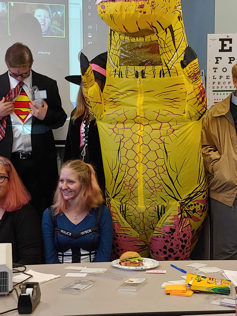 students and big dinosaur costume at fall festival