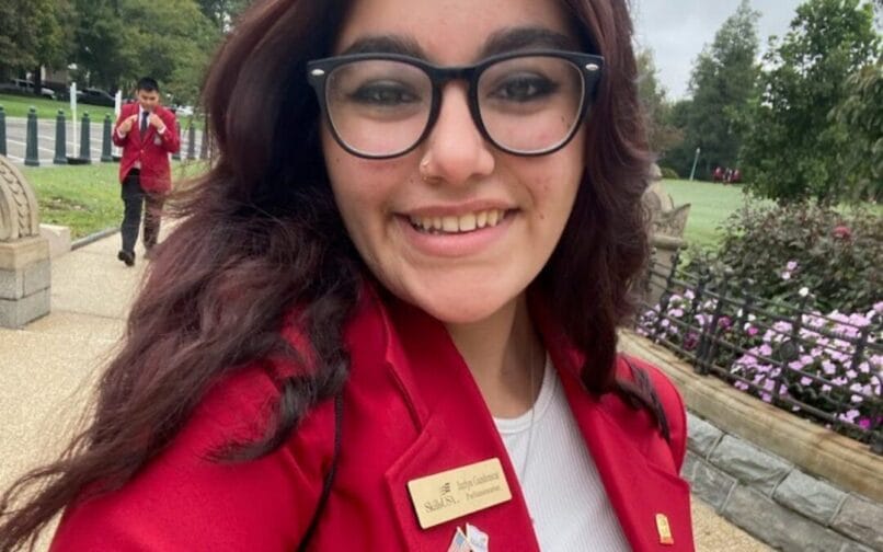 Girl wearing glasses and a red coat taking a selfie